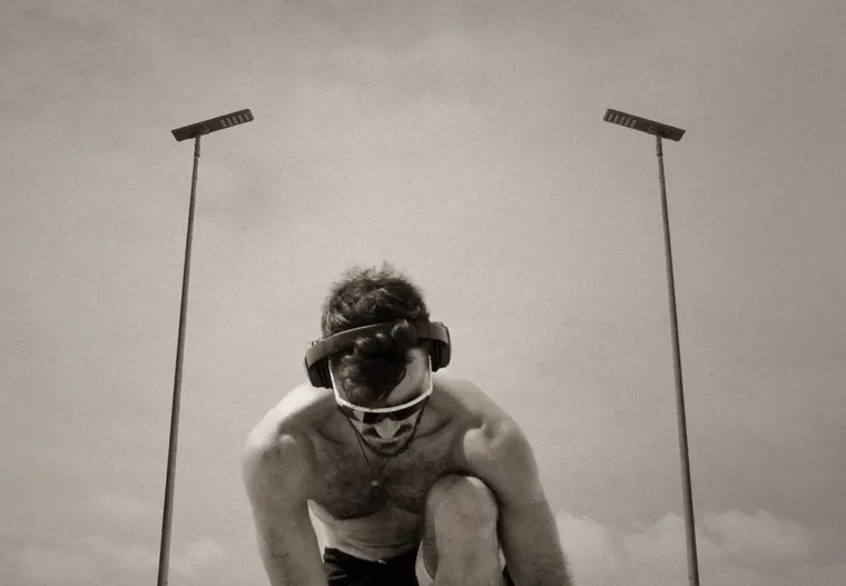 Atleet met koptelefoon tegen een dramatische wolkenlucht