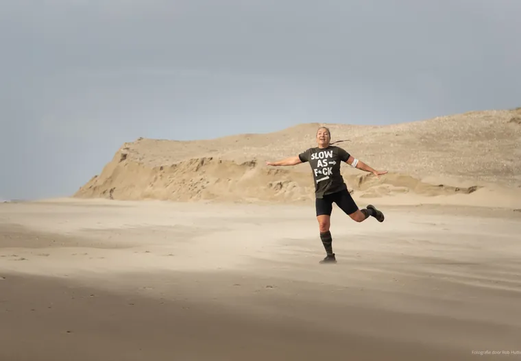 Sporter springt uitgelaten over het strand bij de duinen
