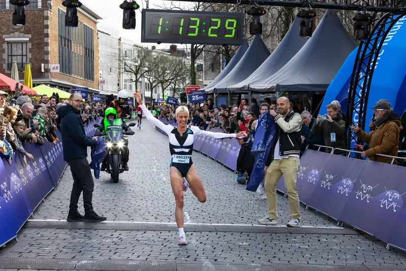 Winnares komt met gespreide armen over de finish van de Stevensloop