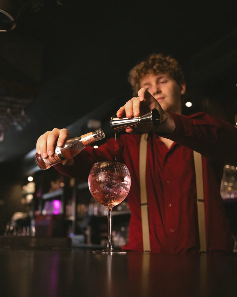 Bartender schenkt een cocktail af achter de bar van YUCA