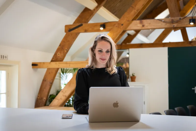 Onderneemster aan het werk achter haar laptop in een licht zolderkantoor