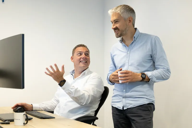 Twee collega's lachen samen tijdens een overleg op kantoor