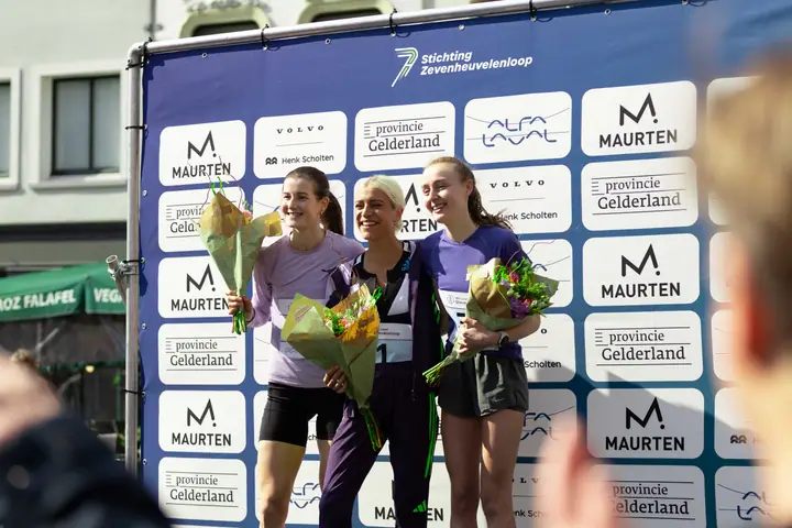 Top drie bij de vrouwen staat stralend met bloemen op het podium van de Stevensloop