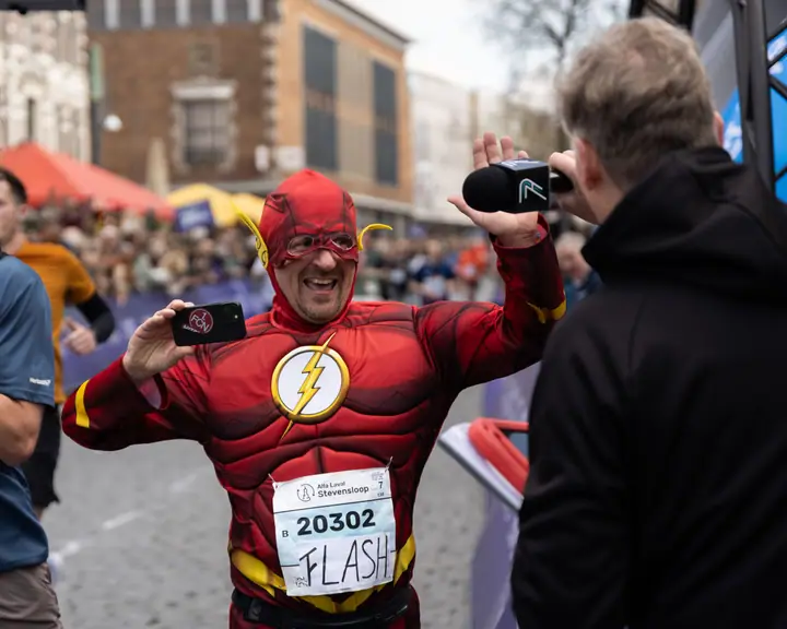 Loper verkleed als The Flash wordt na de finish geïnterviewd en filmt zelf mee