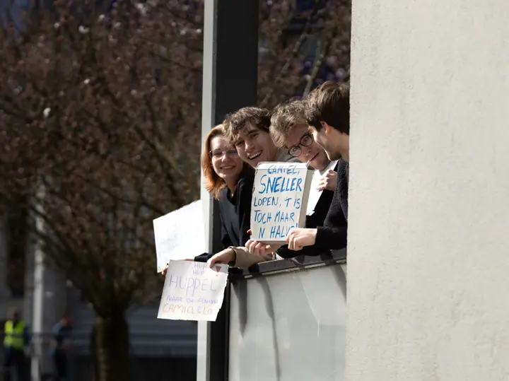 Jongeren op een balkon houden zelfgemaakte bordjes omhoog om een loper aan te moedigen