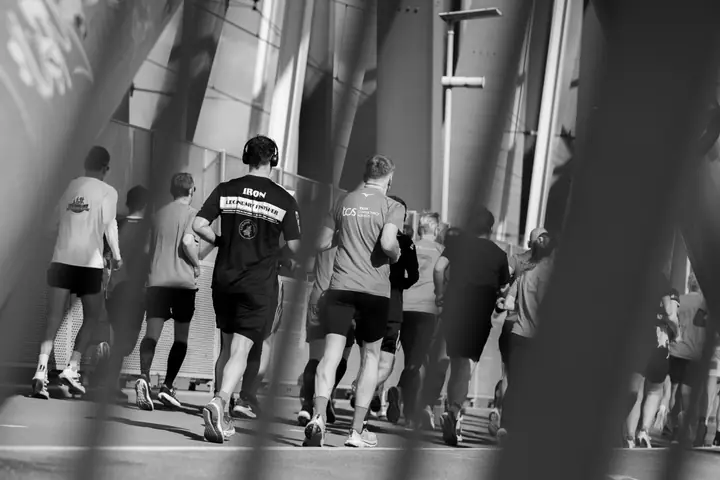 Lopers in zwart-wit van achteren gezien, ingelijst door het staal van de brug