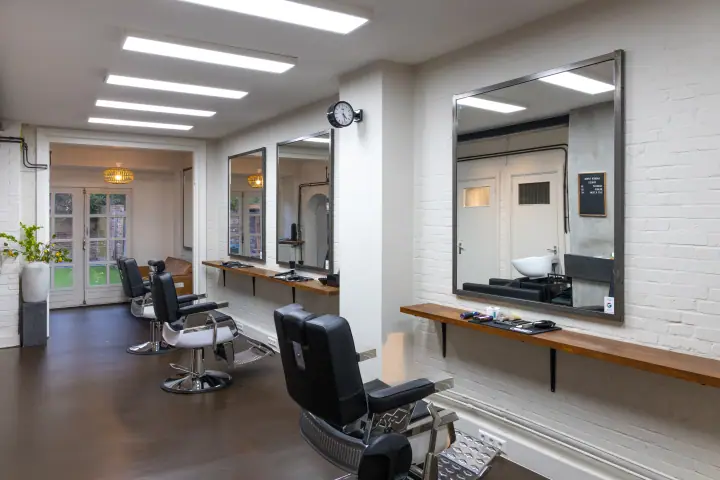 Interieur van ARK Barbershop met zwarte kappersstoelen, grote spiegels en witte bakstenen muren