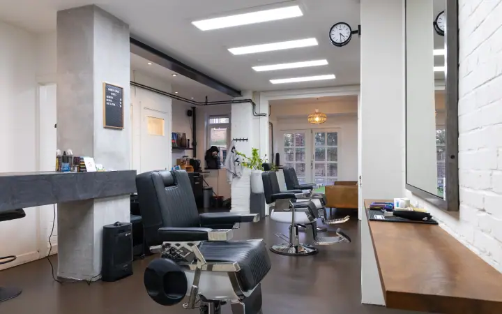 Doorkijk door de barbershop, van de betonnen pilaar met letterbord tot de tuindeuren achterin