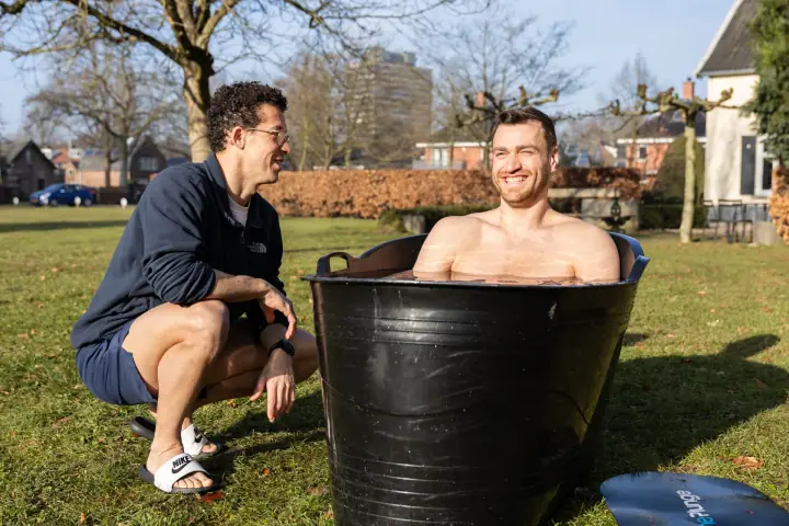 Brede grijns in het ijsbad tijdens de Chakana Coaching workshop, de coach lacht ernaast