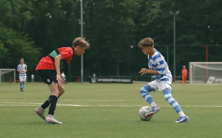 Jeugdspeler van De Graafschap probeert met een schijnbeweging langs zijn directe tegenstander van NEC te komen