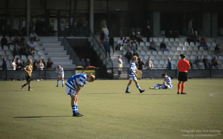 Speler van De Graafschap buigt voorover, een teamgenoot zit op het gras en de scheidsrechter wacht