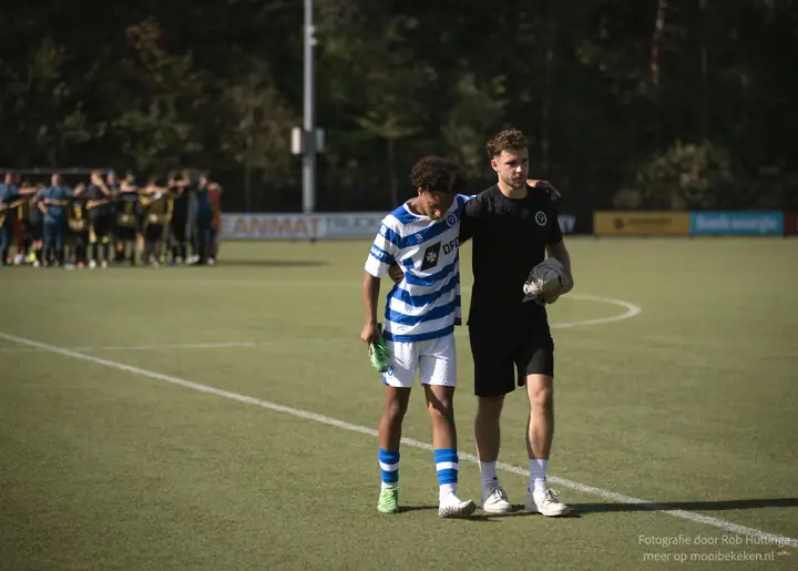 Staflid slaat een arm om een speler van De Graafschap bij het verlaten van het veld