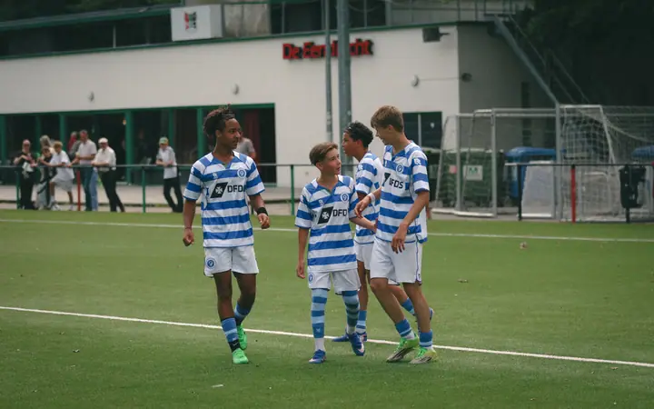 Vier spelers van De Graafschap lopen samen terug naar de middenlijn na een doelpunt