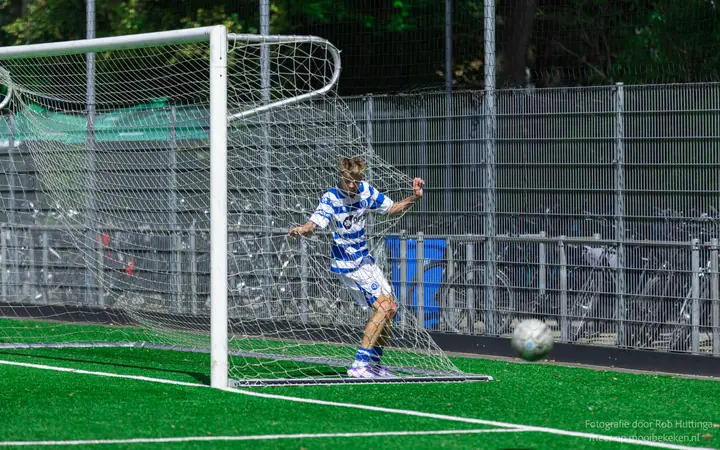 Speler van De Graafschap staat in het doel tegen het net, de bal rolt het veld weer op