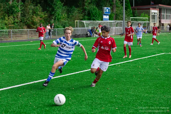 Sprintduel om een losse bal tussen een speler van De Graafschap en een tegenstander in rood