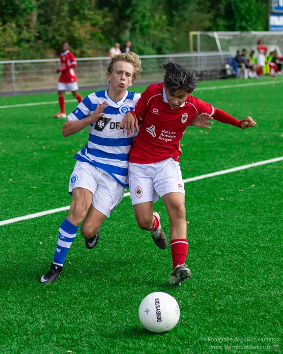 Speler van De Graafschap zet zijn schouder in tegen een tegenstander in rood in het gevecht om de bal