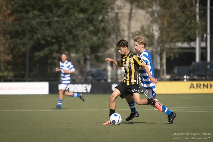 Vitesse-speler gaat er met de bal vandoor, op de hielen gezeten door een speler van De Graafschap