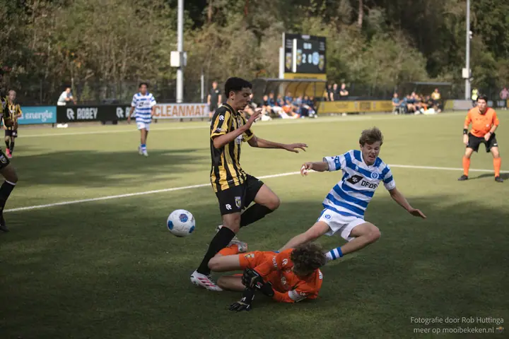 Speler van De Graafschap tuimelt over de keeper heen, een Vitesse-speler loopt naar de losse bal