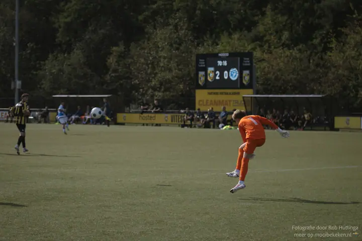 Doelman trapt de bal ver uit, met het scorebord op de achtergrond