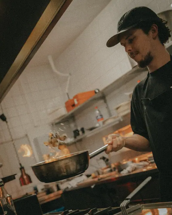 Kok in de keuken van Jadda laat de inhoud van een hete pan door de lucht vliegen