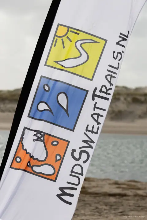 Beachvlag van MudSweatTrails.nl met het logo van een zon, zweetdruppels en een modderige schoen