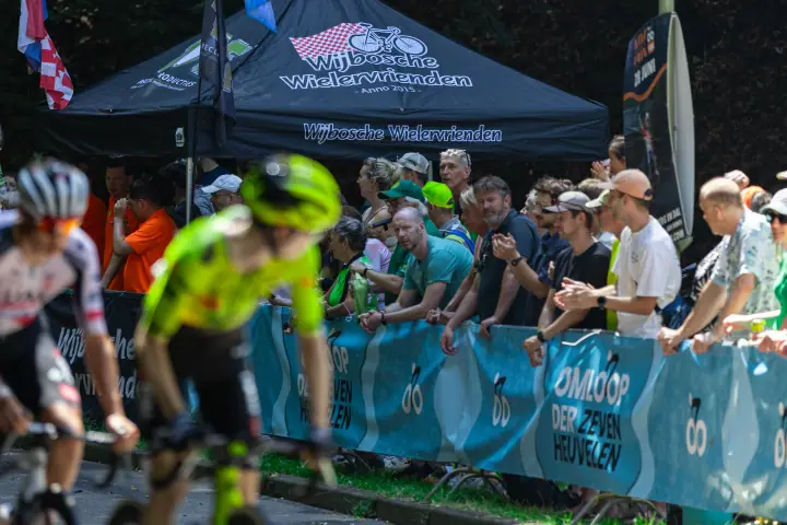 Supporters bij de tent van de Wijbosche Wielervrienden moedigen voorbijflitsende renners aan langs de Omloop der Zevenheuvelen
