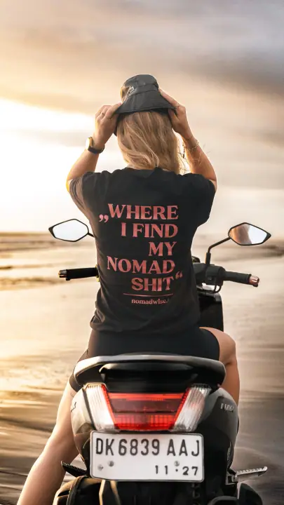 Met beide handen op haar vissershoedje zit ze op de scooter, de roze print op haar rug in beeld