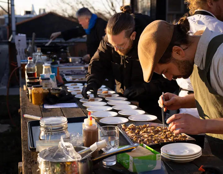 Koks maken buiten de borden op aan een lange houten tafel tijdens het Innoboost-event