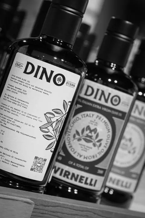 Zwart-wit: een rij DINO-flessen schuin in beeld, met het achteretiket vooraan